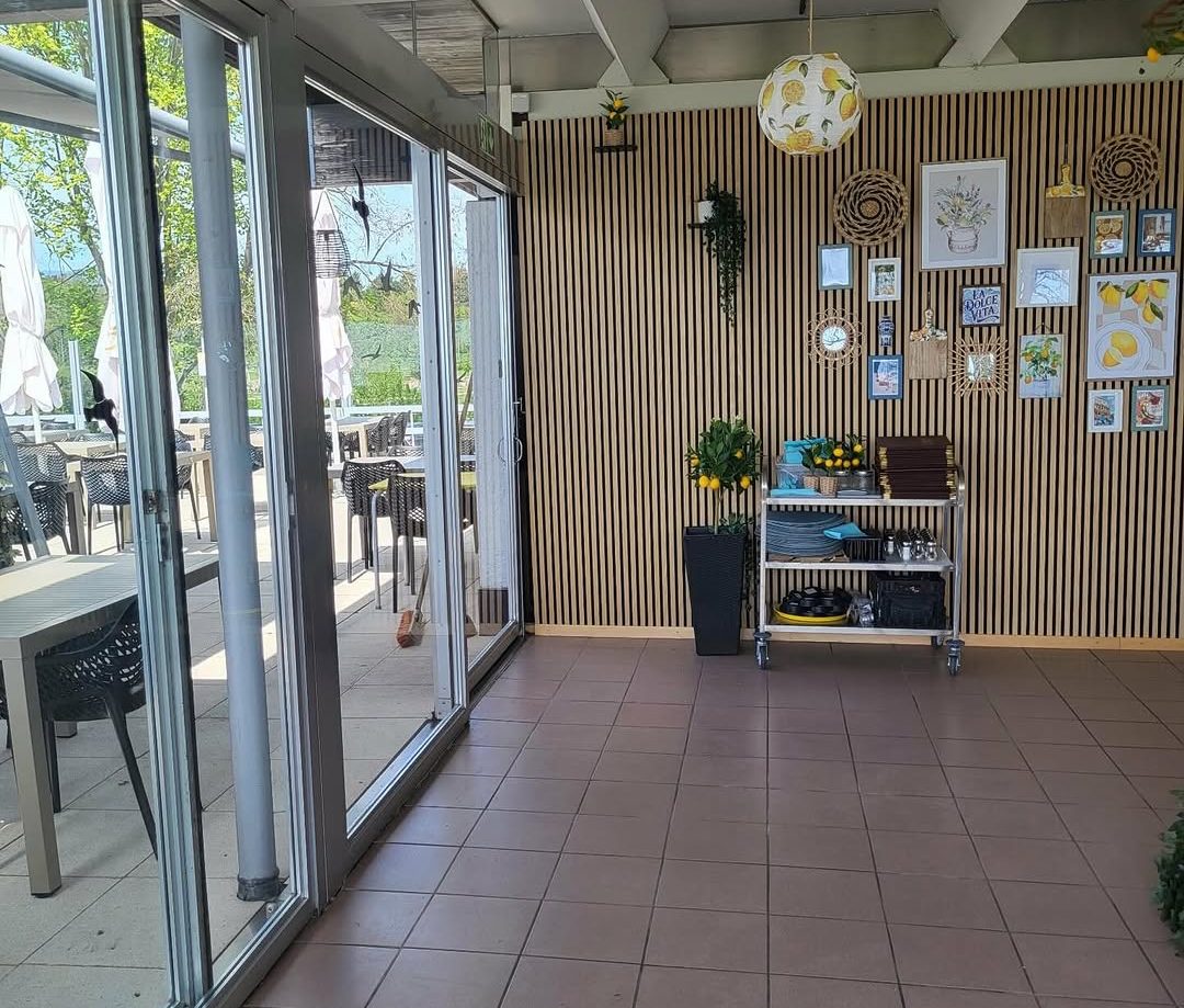 Salle de restaurant lumineuse et propres, grandes baies vitrées ouvertes sur la terrasse